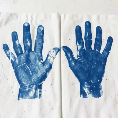 A child's hand and an adult's hand — two scales of cyanotype body print side by 