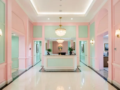 Perfectly symmetrical hotel lobby in pastel pink and mint green, bell counter ce