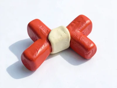 Spunky chunky clay slingshot toy in cherry red with stubby cream-toned band and