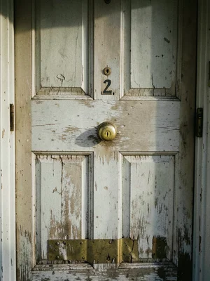 A wooden front door showing its age — the original paint color visible only in t