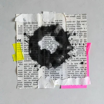 Collage of overlapping newsprint clippings and a single ink blot, soft daylight