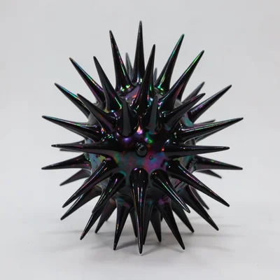 Ferrofluid sculpture responding to hidden magnet, spiky black form, iridescent s