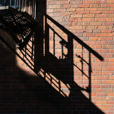 Shadow of fire escape falling across brick wall, geometry casting geometry