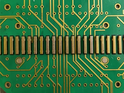 A close-up of a connector row on a PCB — gold-plated edge fingers in a repeating