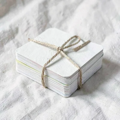 Cut-paper still life of a stack of folded language flashcards bound with twine,