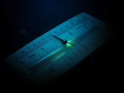 Slide rule cursor line over logarithmic scale, transparent hairline on engraved 