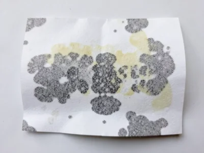 Receipt paper with water damage, thermal coating bloomed into abstract dark patc