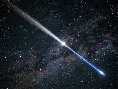 A comet with a bright coma and two tails — the white dust tail curving gently, t