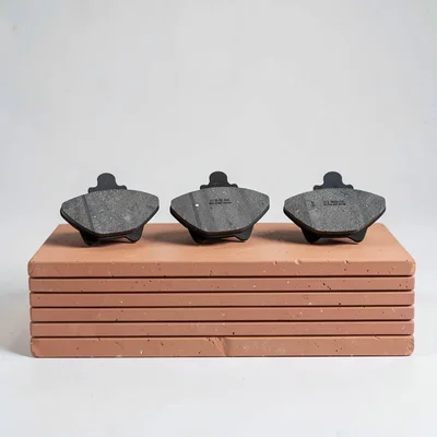 Catalog ad of three brake pads in a row on a terracotta block with horizontal rh