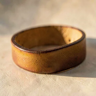 Macro of an edge-burnished leather band with smoothed slope, side-lit honey colo