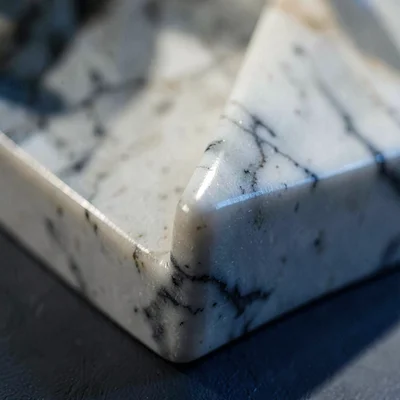 Mineral-cut close-up of a polished marble sculpture detail with a single sharp e