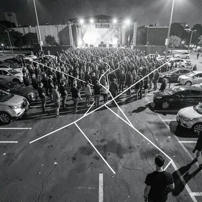 Crowd dispersing after concert, paths diverging like human mitosis, parking lot 