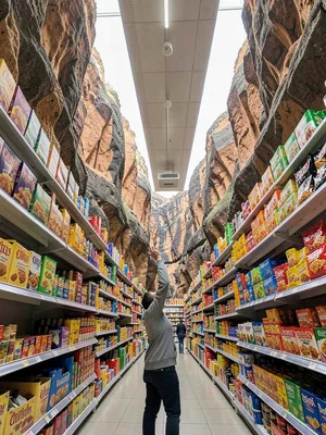 Standing in grocery aisle looking up, shelves warping into canyon walls, product